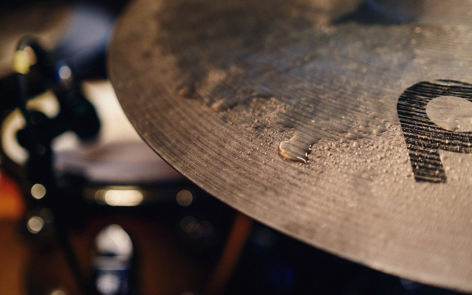 Close-up of a drum cymbal with water droplets scattered across its textured surface